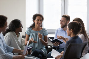 Group of people sitting on chairs in circle, talking